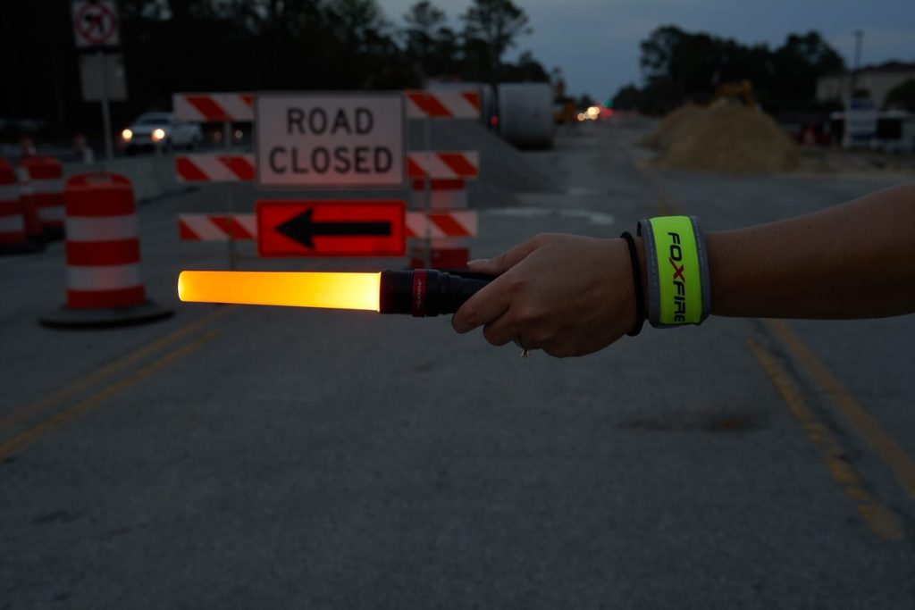 traffic control light wand held in front of a road closed sign